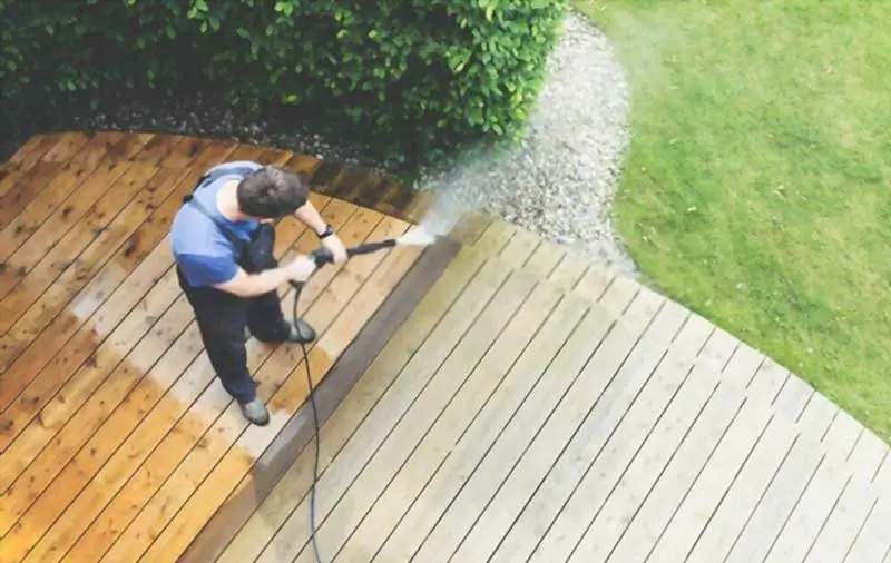 Man cleaning terrace with a power-washer & mold cleaner for wood